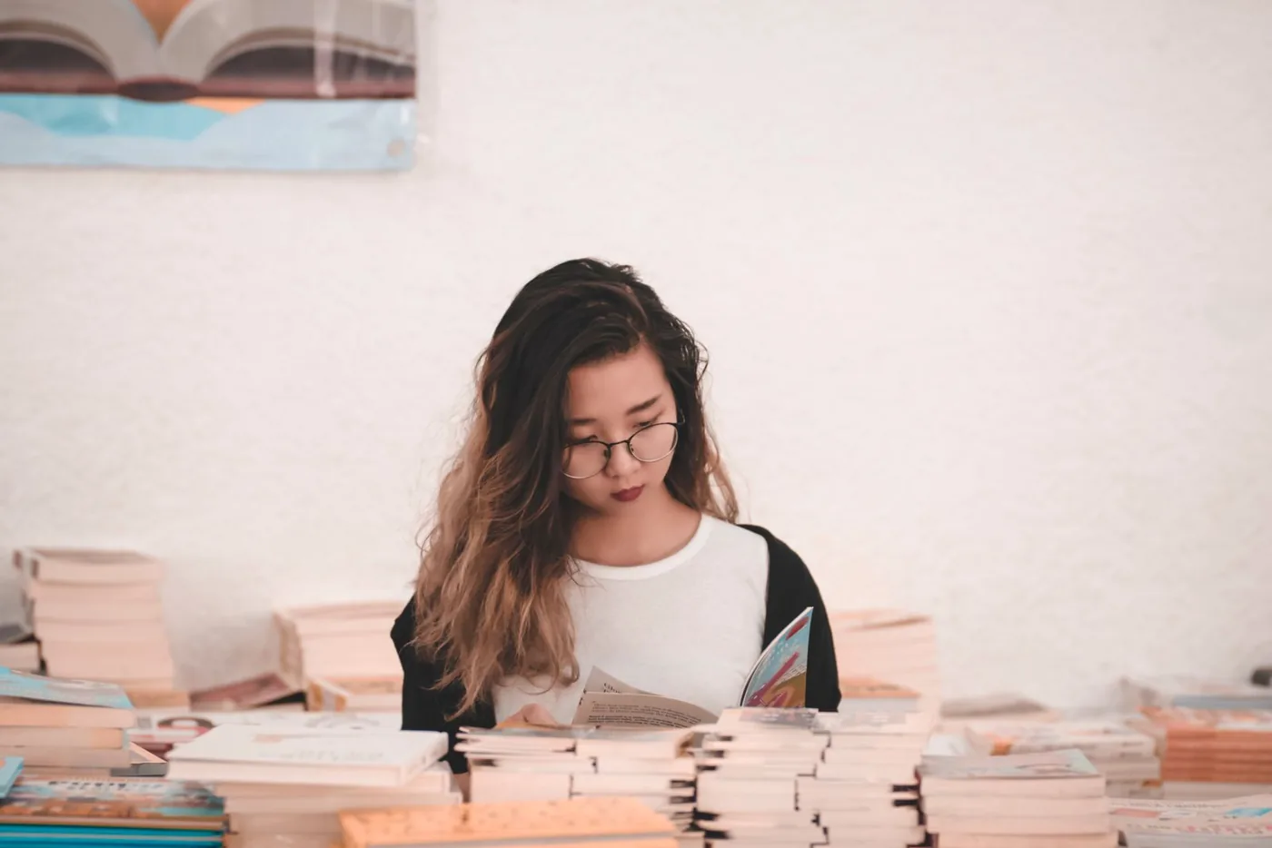 Cô gái đeo kính đọc sách giữa những chồng sách